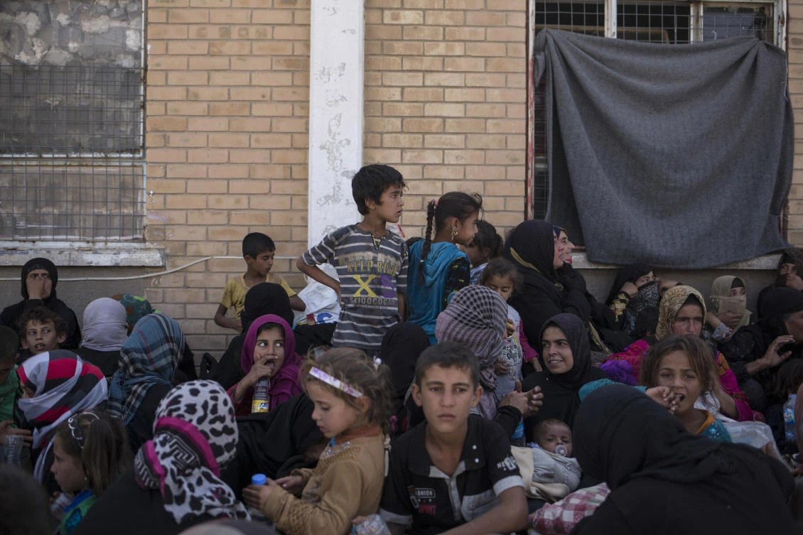 Women and children sit outside a Kurdish screening center to determine if they are associated with Daesh in this October 3, 2017 photo taken in Dibis, Iraq. (AP)