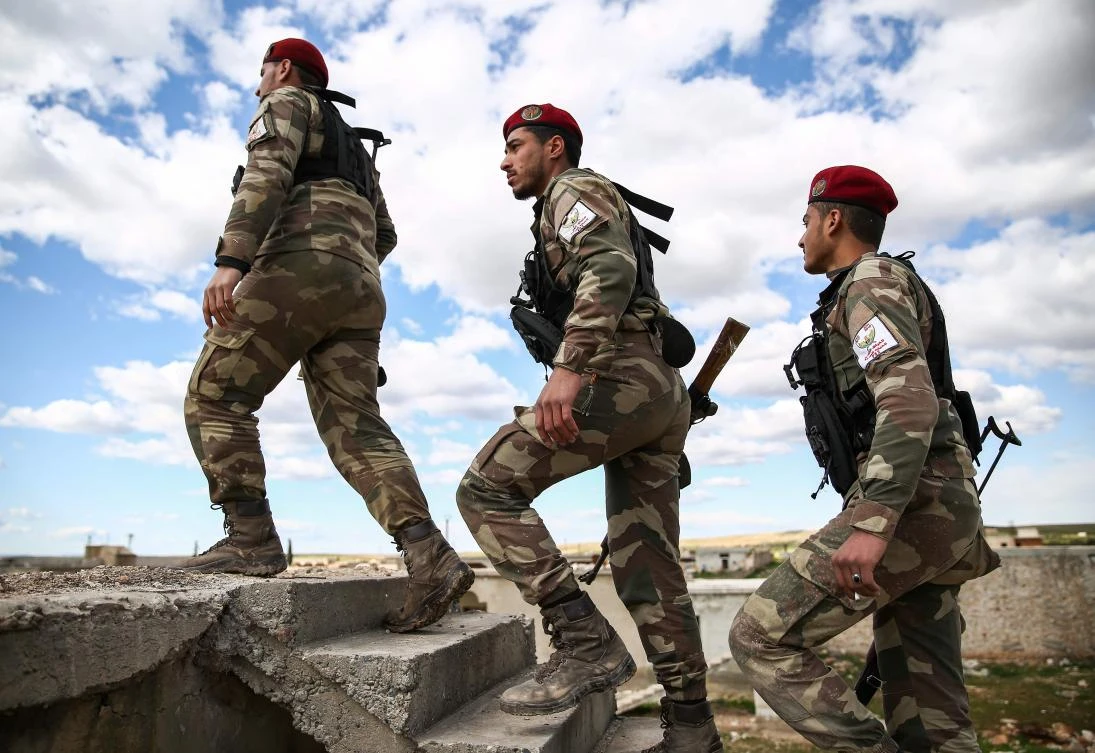 Syrian fighters of the Turkish-backed Hamza Division walk on patrol along positions in the village of Ulashli near the frontline in the northeast of Aleppo province on March 7, 2019. (AFP/Nazeer Al-Khatib)