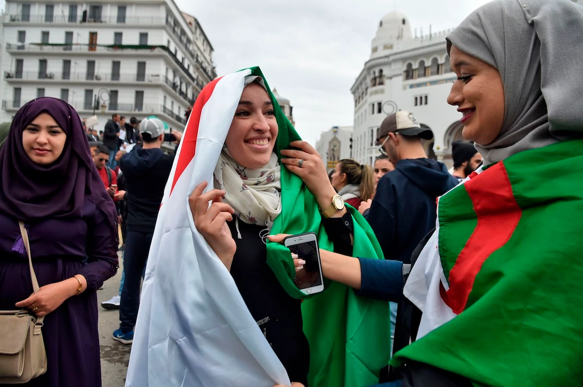 Algerian female protesters wear their national flags as they demonstrate against their ailing president's bid for a fifth term in power, in Algiers on March 8, 2019. (AFP)
