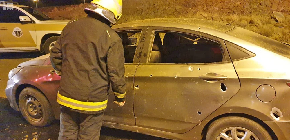 A Civil Defense firefighter inspects a car damaged by falling debris from a Houthi drone that was shot down by Saudi Air Defense Forces over the city of Abha on Friday. (SPA)