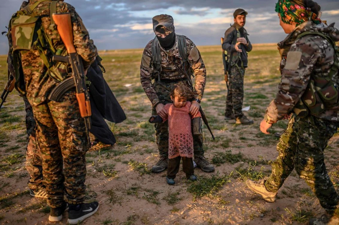 A member of the Kurdish-led Syrian Democratic Forces (SDF) holds a toddler during a security check of her and her mother (unseen) after they left the Daesh group's last holdout of Baghouz, in Syria's northern Deir Ezzor province on February 27, 2019. (AFP/Bulent Kilic)