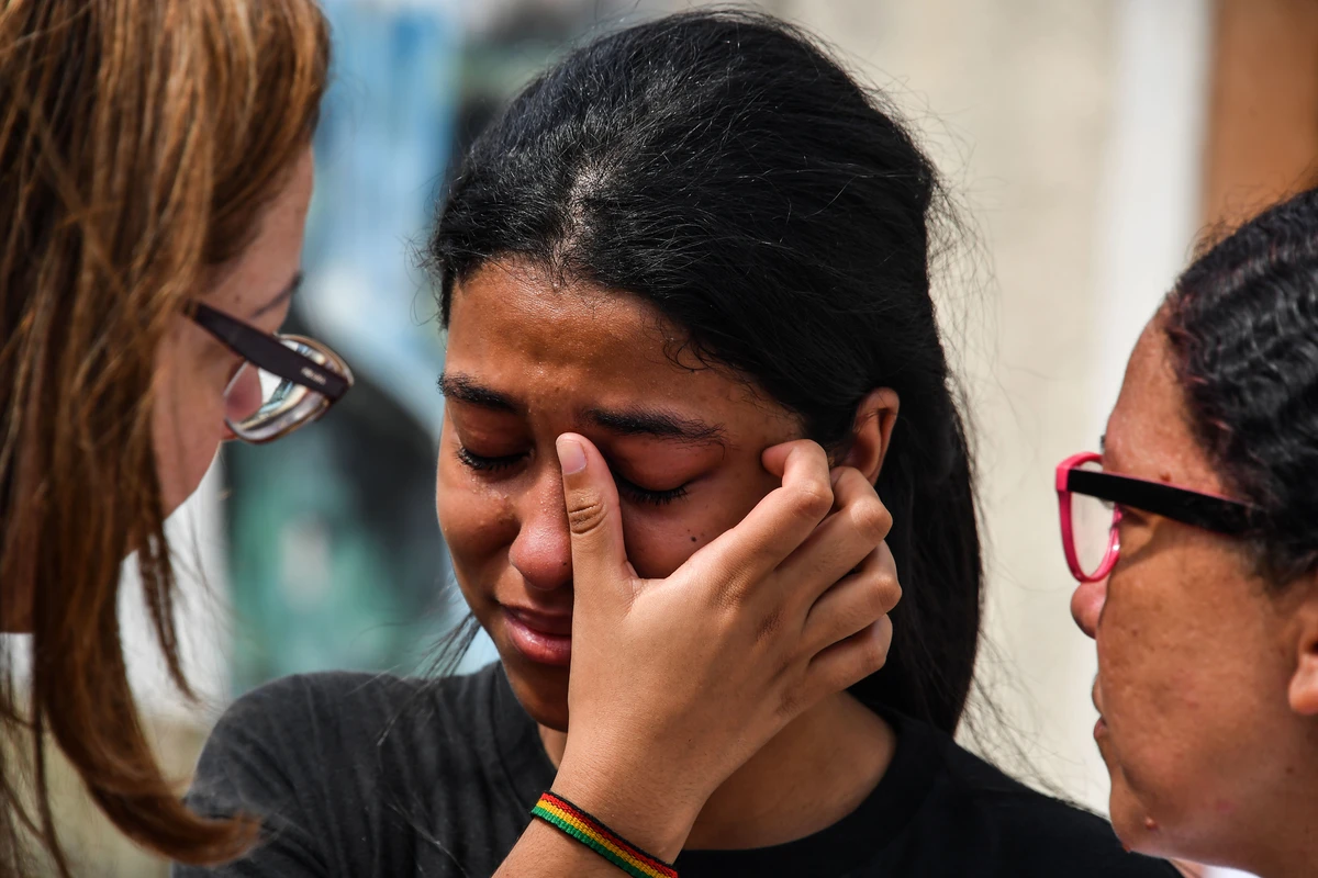 A student from Raul Brasil public school in Suzano, Sao Paulo metropolitan region, Brazil, is comforted while she cries after a shooting took place at the education center on March 13, 2019. (Nelson Almeida/AFP)