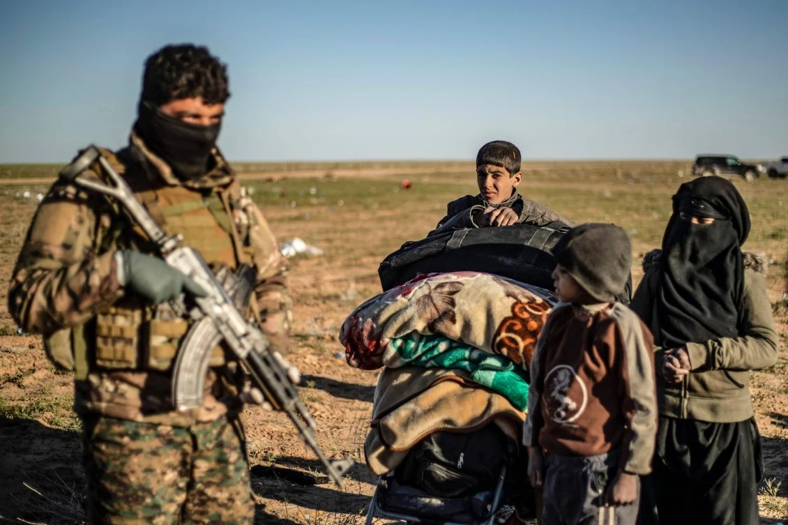 Women and children walk with their belongings as they are directed by members of the Kurdish-led Syrian Democratic Forces (SDF) after leaving Daesh's last holdout of Baghouz, in the eastern Syrian Deir Ezzor province on March 1, 2019. (AFP/Delil Souleiman)