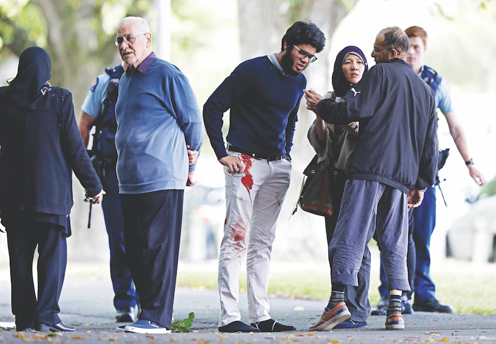 People stand across the road from one of the targeted mosques in Christchurch. (AP)