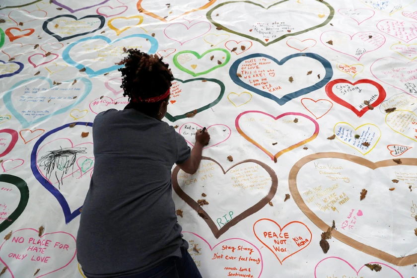 People write on a sign at a memorial as a tribute to victims of the mosque attacks, near a police line outside Masjid Al Noor in Christchurch, New Zealand, on March 16, 2019. (REUTERS/Jorge Silva)