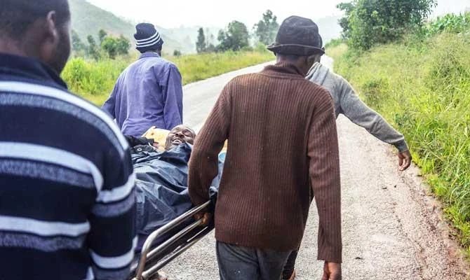 A rescued man cracks jokes while being carried on a stretcher bed by friends on March 18, 2019 in Ngangu township, Chimanimani, Manicaland Province, eastern Zimbabwe, after the area was hit by the cyclone Idai. (AFP)