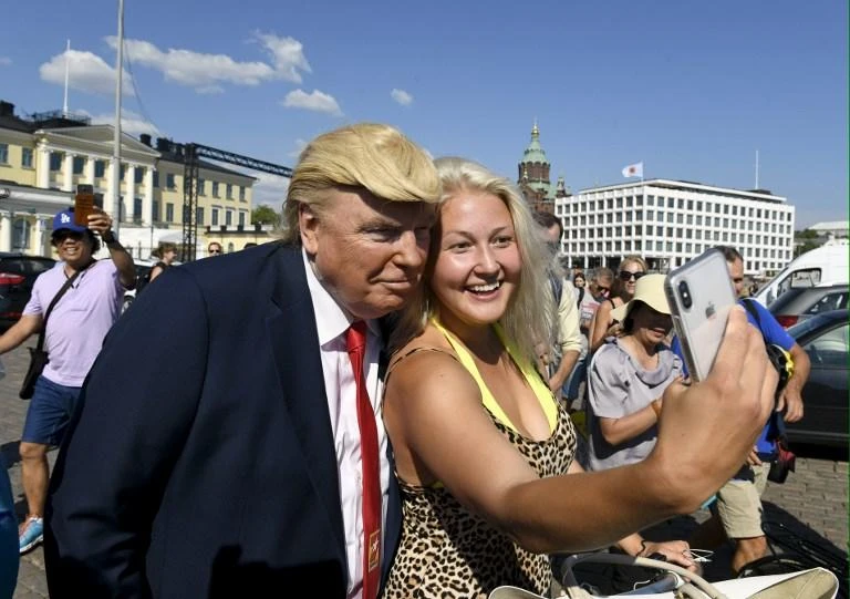A Finnish resident takes a picture with US President Donald Trump impersonator Dennis Alan in front of the presidential palace in Helsinki in this July 15, 2018 photo. (AFP)