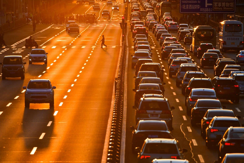 A pedestrian walks on a crossing next to cars in the traffic on a main road during sunset in Beijing, China, on March 21, 2019. Authorities say a driver rammed his car into a crowd in central China on Friday, killing six people and injuring seven others before he was shot dead by the police. (Reuters)