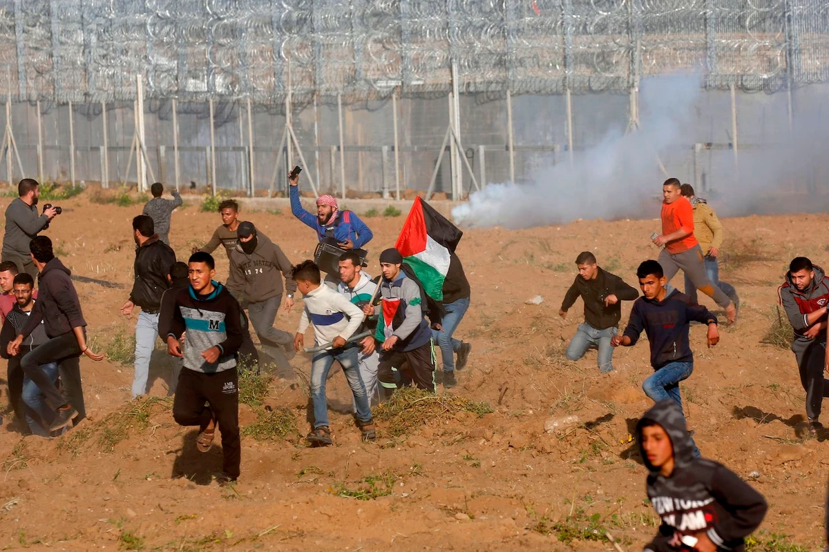 Palestinians flee from tear gas during a protest by the barbed-wire fence with Israel east of Gaza City on March 22, 2019. (AFP)