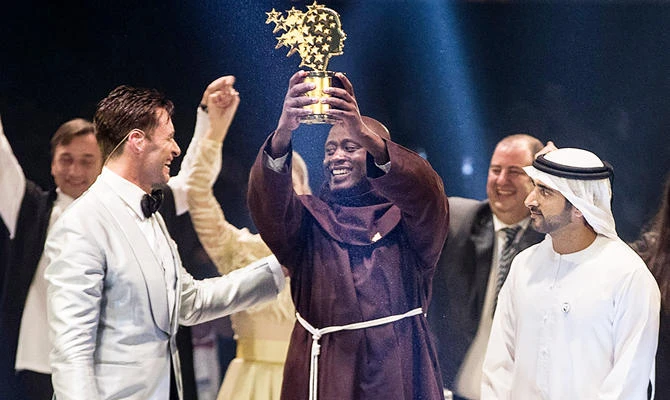 This handout photo provided on March 24, 2019 by the Global Education and Skills Forum, an initiative of the Varkey Foundation, shows Kenyan teacher Peter Tabichi (C) holding up the Global Teacher Prize (GTP) trophy after winning the US$ 1 million award during an official ceremony in Dubai presented by Australian actor Hugh Jackman (C-L) and attended by the Dubai Crown Prince Hamdan bin Mohammed Al-Maktoum (C-R). (AFP)