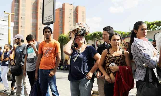 People line up at a bus stop in an attempt to leave the city during a power outage in Caracas, Venezuela, Monday, March 25, 2019. (AP)