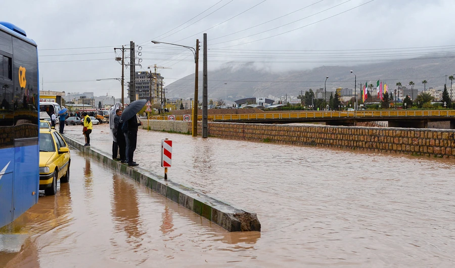 People stand near a flooded street after a flash flooding in Shiraz, Iran, on March 26, 2019. (Reuters)