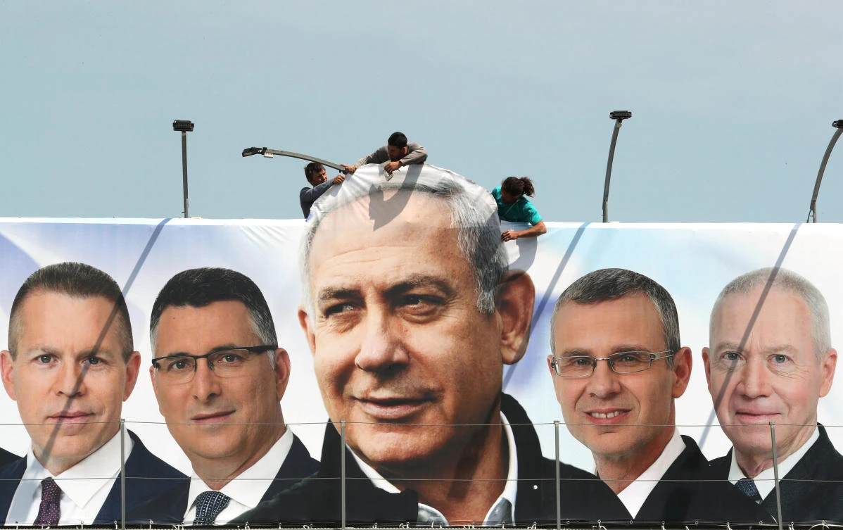 Laborers work on hanging up a Likud election campaign banner depicting Israeli Prime Minister Benjamin Netanyahu with his party candidates, in Jerusalem. (Reuters)