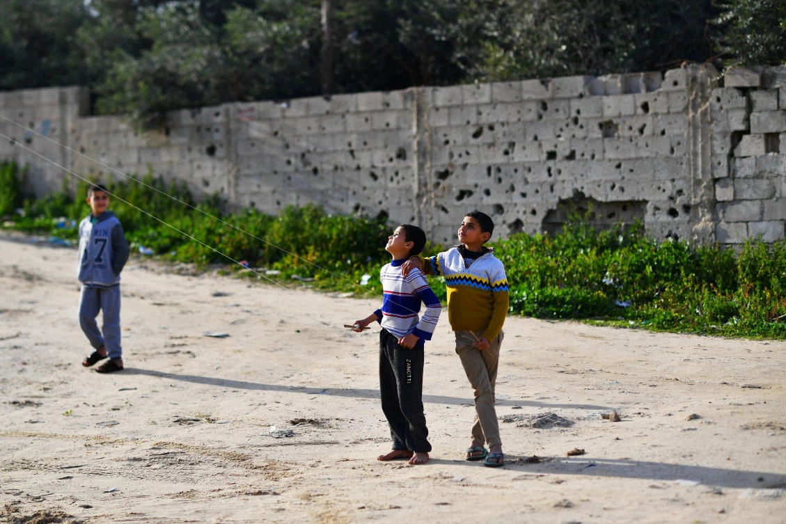 Bullet and shrapnel holes cover a wall as children fly kites in Gaza City, February 12, 2019. (Reuters)