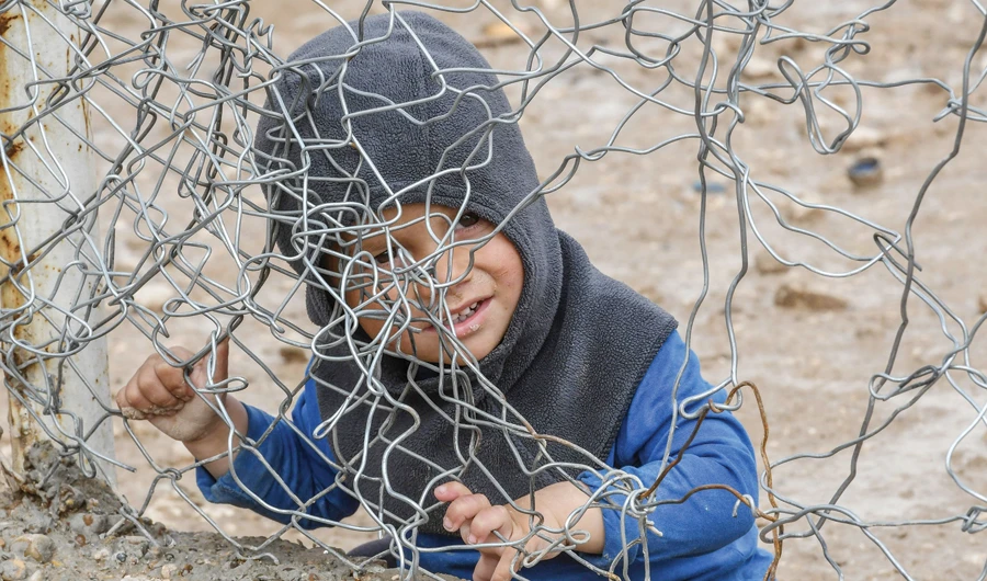 A child sits behind a wire fence in Al-Hol camp, which houses relatives of Daesh members, in northeastern Syria. (AFP)