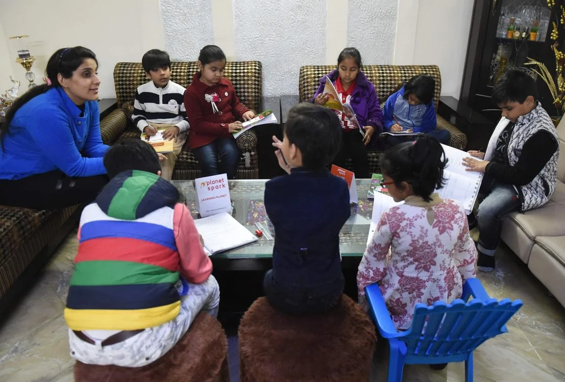 In this photograph taken on February 13, 2019, Ruchi Taneja (L) teaches a group of Indian children studying with an app created by Planet Sparks that uses "gamified" teaching methods at a tuition centre in New Delhi. (AFP)