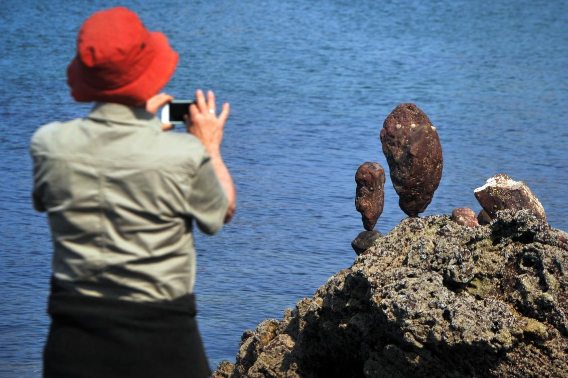 A person takes a photograph of stacks in the European Stone Stacking Championships 2019 in Dunbar, Scotland, on April 21, 2019. The European Stone Stacking Championships are Europe’s largest championships for all Stone Stacking and Rock Balancing artists and practitioners. Stackers compete in four competitions creating sculptures using stones and balancing them using only the force of gravity. The overall winner receives a trip to llano Earth Art Festival and World Stone Balancing competition 2020. / AFP / Andy Buchanan
