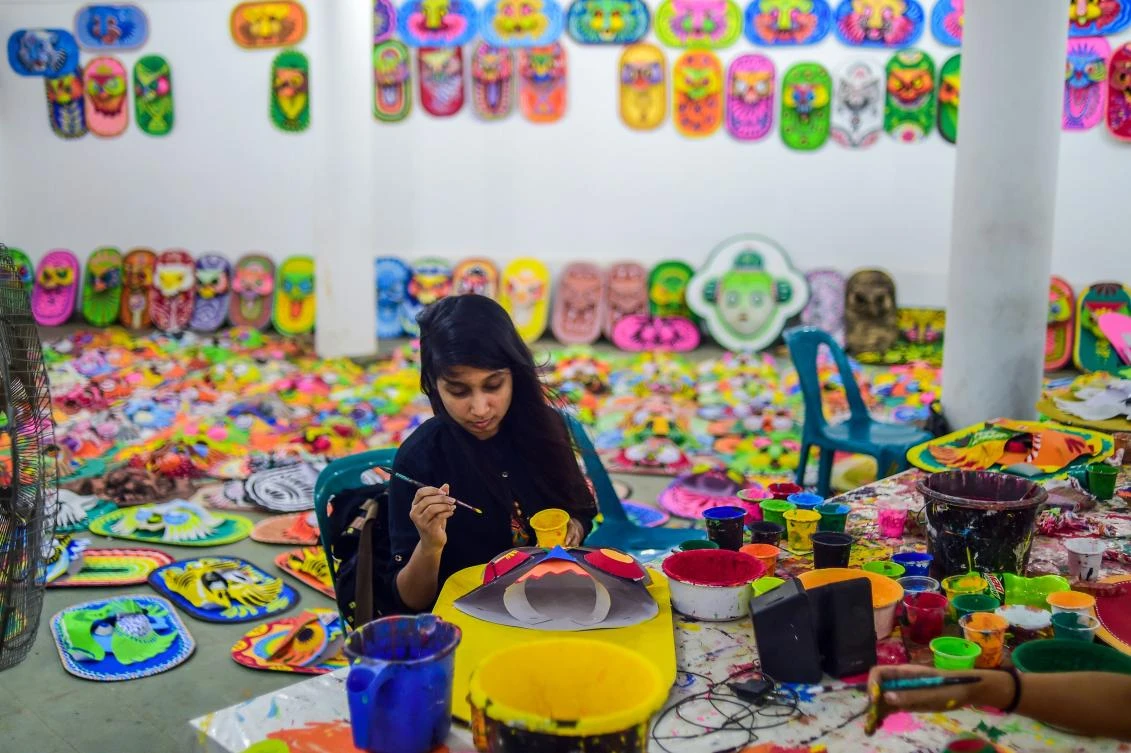 A Bangladeshi student of Dhaka University Art Institute paints a mask to sell as a part of Bengali New Year preparations in Dhaka on April 7, 2019. The Bengali calendar is solar, with the year beginning on Pohela Boishakh, which falls on April 14 this year, in Bangladesh. / AFP / Munir UZ ZAMAN