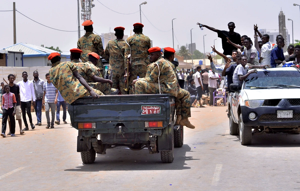 Sudanese demonstrators cheer as they drive towards a military vehicle near the Defense Ministry. (Reuters)
