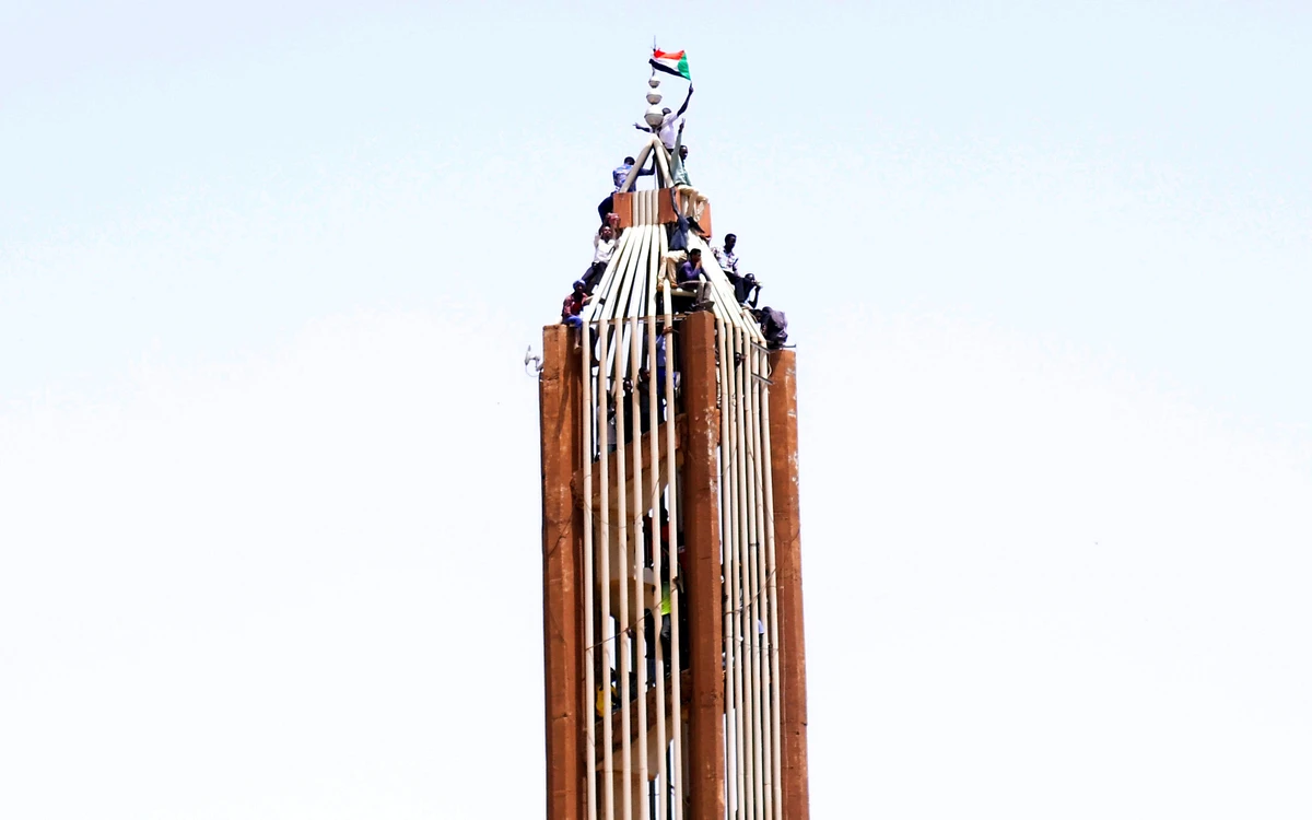 Sudanese demonstrators scale a building in central Khartoum following the ousting of Al-Bashir. (Reuters)