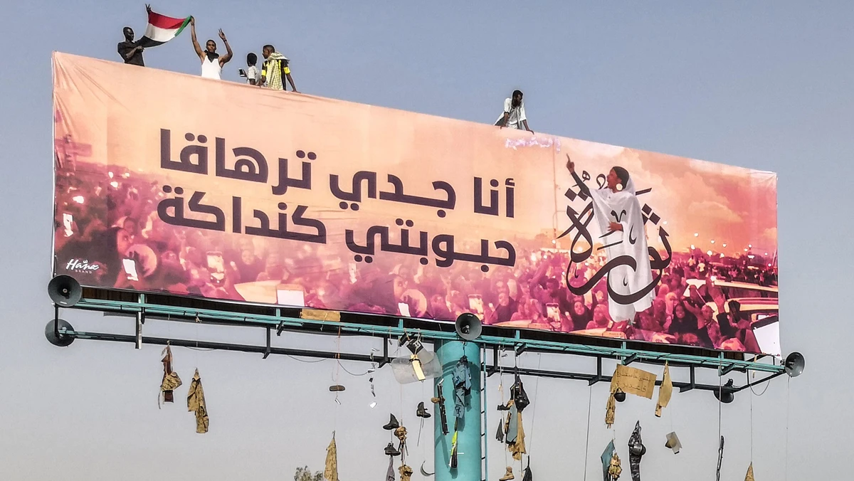 A picture taken during anti-regime protests on April 11, 2019 shows a huge billboard bearing an image of Alaa Salah, a Sudanese woman propelled to internet fame earlier this week after clips went viral of her leading powerful protest chants against Sudan's president, in the Sudanese capital Khartoum. Arabic writing next to her photo in a white gown reads: "My grandfather is Tarhaka, my beloved Kandaka”. (AFP)