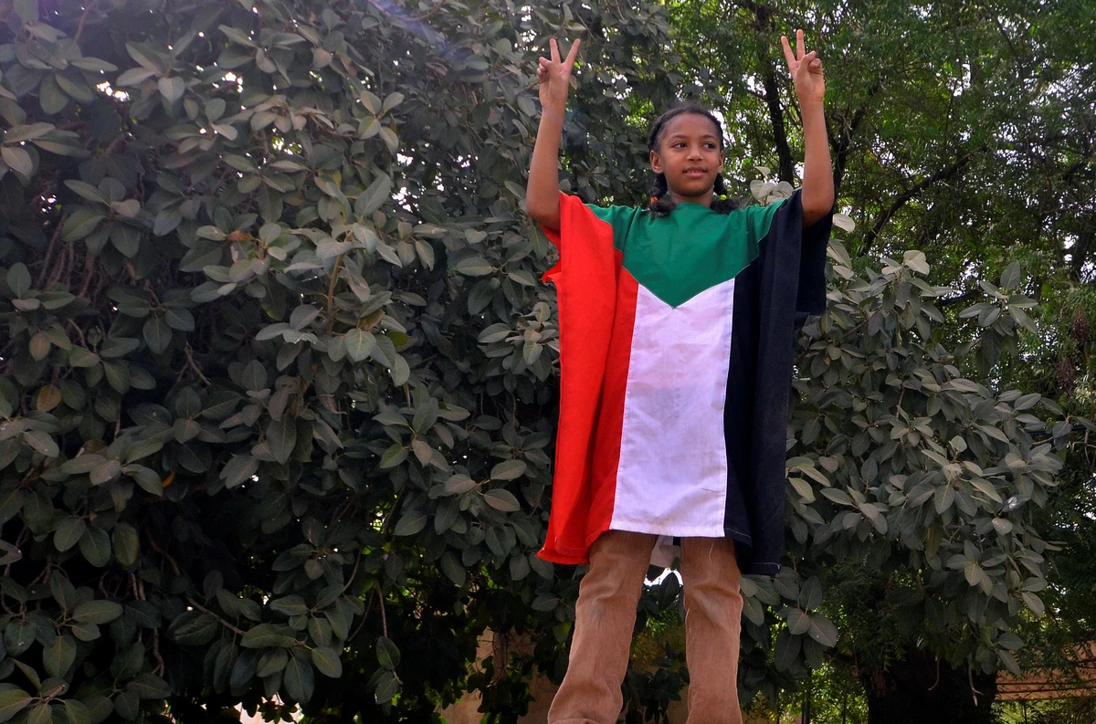 A child dressed in the Sudanese national flag flashes V signs along the streets. (Reuters)