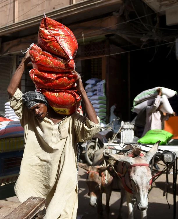 A Pakistani labourer carries sacks of rice at a market in Karachi on April 30, 2019, on the eve of the International Labour Day celebrated on May 1. / AFP / RIZWAN TABASSUM