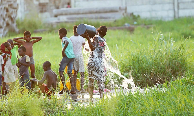 A young girl splashes water on her body at a watering point in Beira, Mozambique, Monday, April, 1, 2019. (AP)