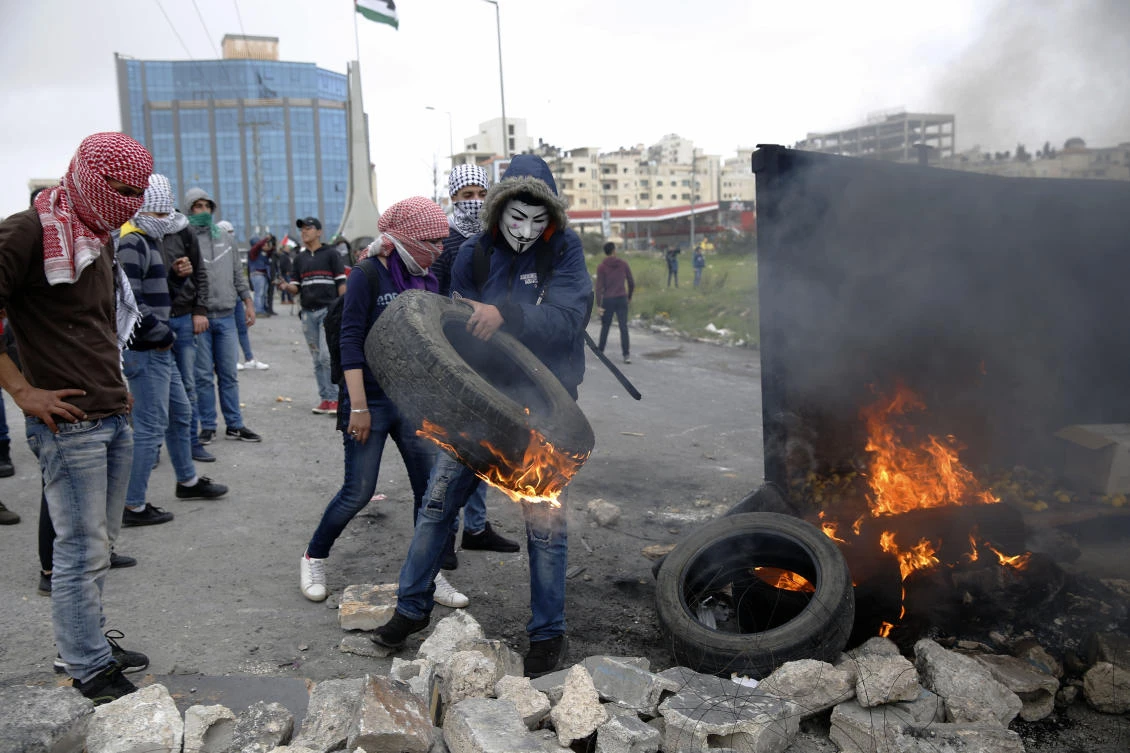 A Palestinian carries a burning tire during clashes with Israeli forces at checkpoint Bet El near the West Bank city of Ramallah on Saturday, March 30, 2019. (AP)