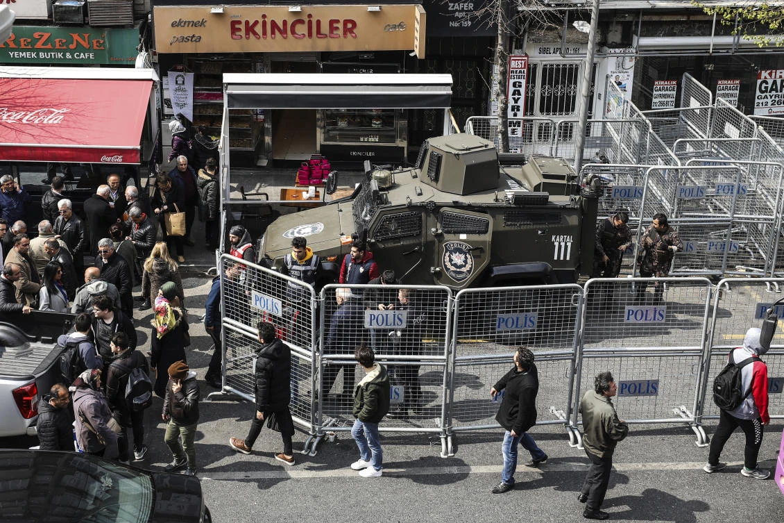 People walk past barriers surrounding the Supreme Election council building, guarded by police officers, Tuesday April 2, 2019 in Istanbul. (AP)