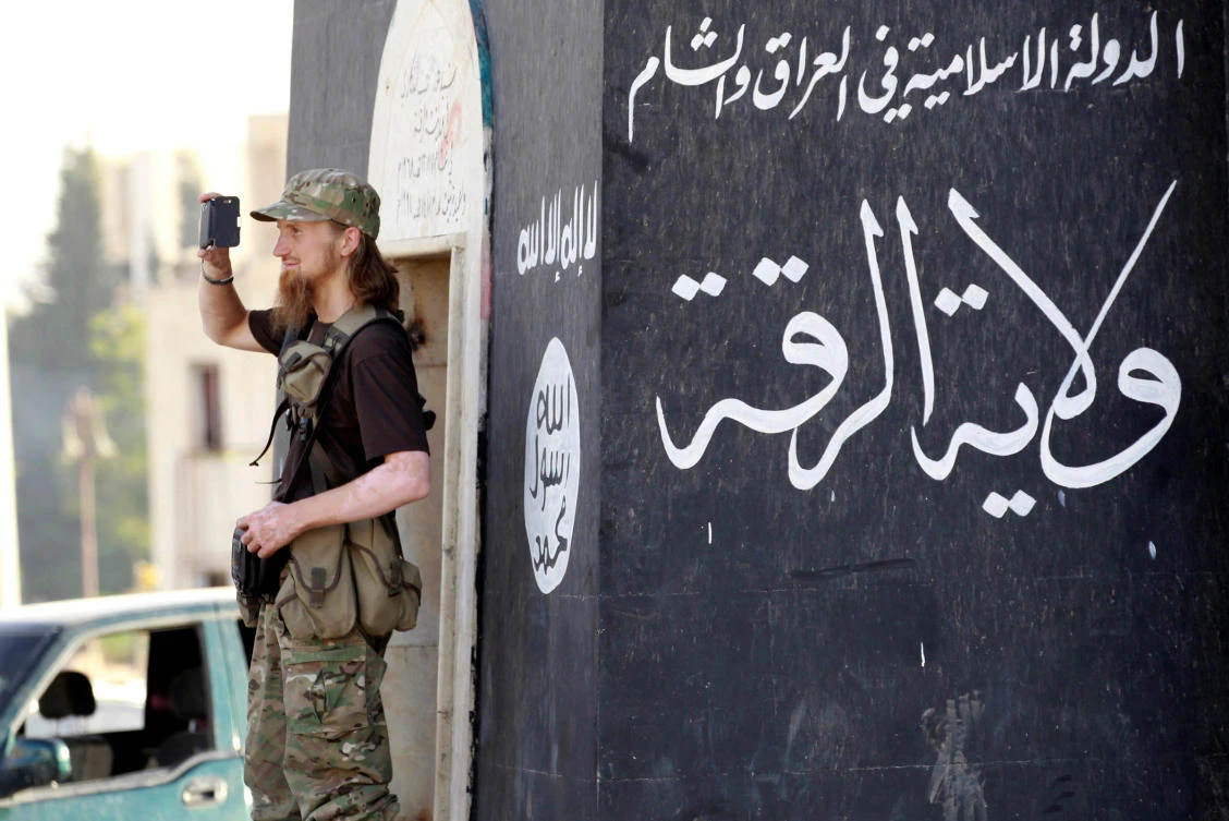 File photo shows a militant Islamist fighter use a mobile phone to film his fellow fighters who are taking part in a military parade along the streets of Syria's northern Raqqa province June 30, 2014. (Reuters)