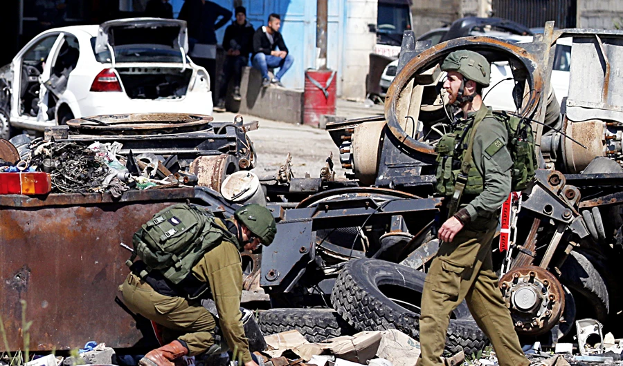 Israeli soldiers inspect the site where a Palestinian man was killed after he reportedly tried to stab an Israeli driver at a junction south of Nablus on Wednesday. (AFP)