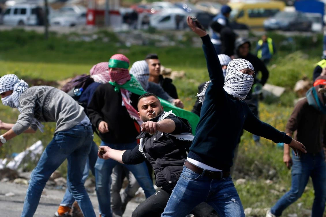 Palestinian protesters hurl rocks at Israeli troops during a protest on the outskirts of Ramallah in the occupied West Bank on March 27, 2019. (AFP)