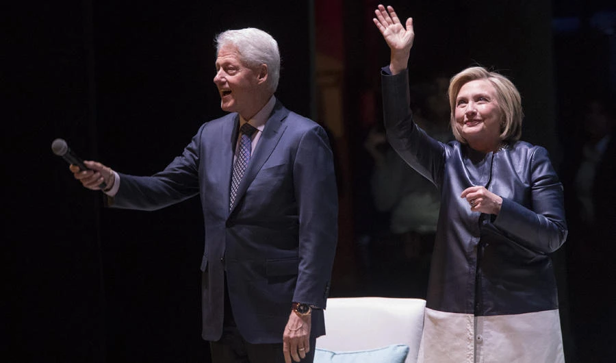 Former President Bill Clinton, left, and former Secretary of State Hillary Rodham Clinton wave at the crowd as they arrive on stage for "An Evening with the Clintons", on April 11, 2019, at the Beacon Theatre in New York. (AP Photo/Mary Altaffer)