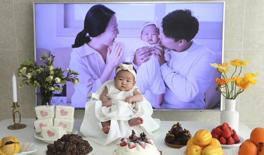 In this April 9, 2019, photo, Lee Dong Kil's daughter Lee Yoon Seol sits to celebrate her the 100th day of the birth at Lee's house in Daejeon, South Korea. Just two hours after Lee's daughter was born on New Year's Eve, the clock struck midnight, 2019 was ushered in, and the infant became 2-years-old. (AP Photo/Ahn Young-joon)
