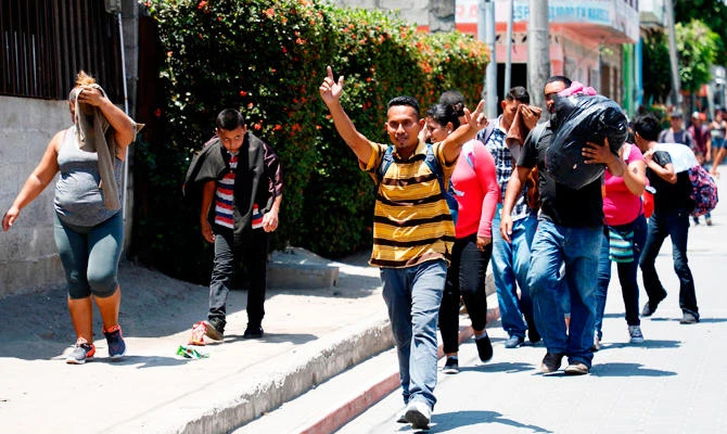 Migrants break border gate, force their way into Mexico