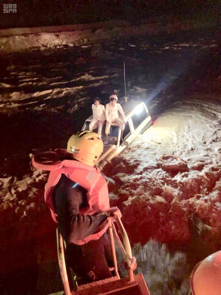 A civil defense unit comes to the rescue of two young men perched atop their vehicle that got trapped in flood in in Riyadh province on April 13, 2019. (SPA)