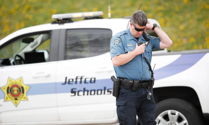 An officer from Jefferson County, Colo., Schools listens on his radio as students leave Columbine High School late Tuesday, April 16, 2019, in Littleton, Colo. (AP)