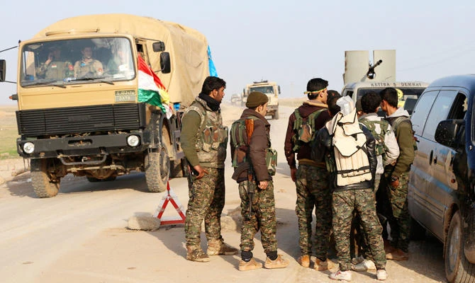 Military vehicles pass as Kurdish People's Protection Units (YPG) and Kurdistan Workers Party (PKK) fighters man a checkpoint on a highway connecting the Iraqi-Syrian border town of Rabia and the town of Snuny north of Mount Sinjar December 20, 2014. (REUTERS)