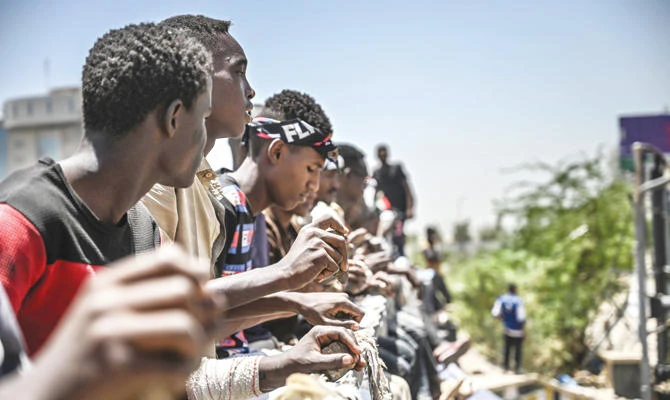 Sudanese protesters tap the rails of a bridge with stones during a protest near the military headquarters in Khartoum on Sunday. (AFP)