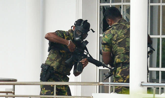 Sri Lankan Special Task Force (STF) personnel in gas masks are pictured outside a house during a raid -- after a suicide blast had killed police searching the property -- in the Orugodawatta area of the capital Colombo on April 21, 2019, following a series of blasts in churches and hotels. (AFP)