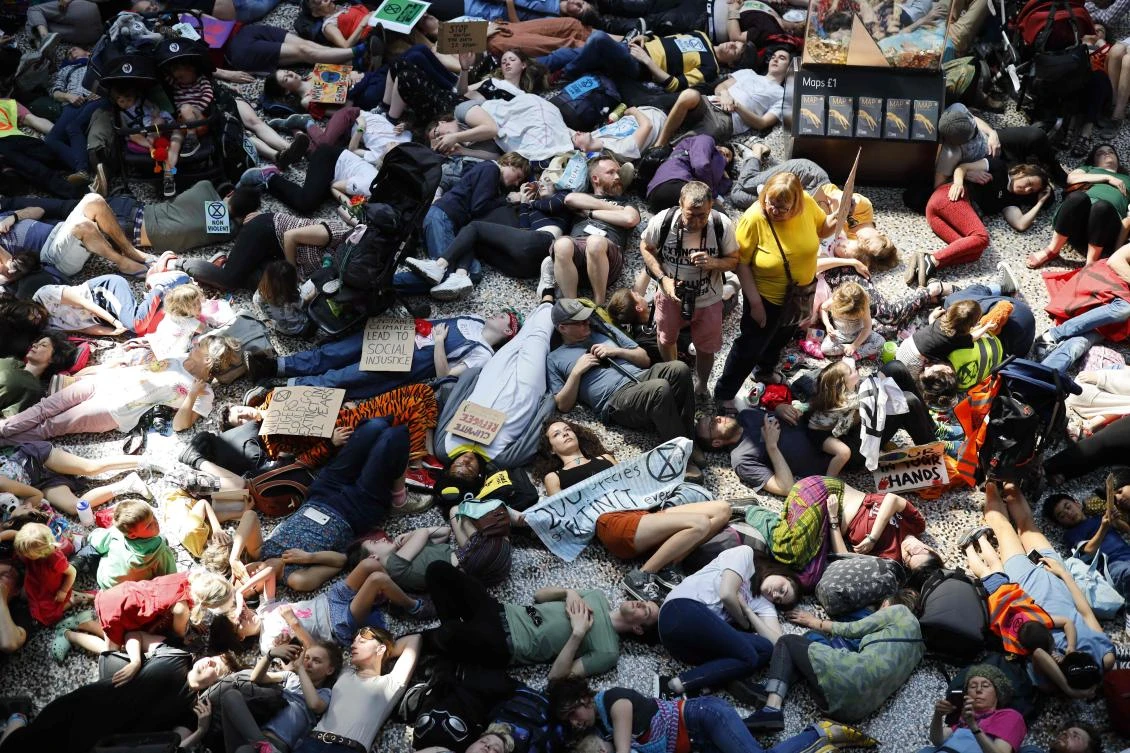Extinction Rebellion climate change activists lie on the floor as they perform a mass "die in" in the main hall of the Natural History Museum in London on April 22, 2019, on the eighth day of the environmental group's protest calling for political change to combat climate change. (AFP)