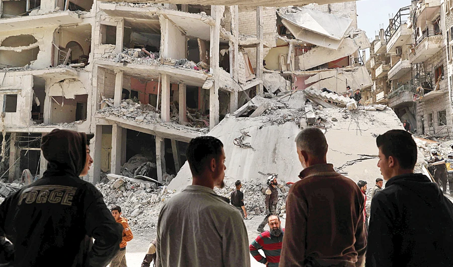 People watch as members of the Syrian Civil Defense search the rubble of a collapsed building following an explosion in the town of Jisr Al-Shughour, in the Syrian province of Idlib, on Wednesday. (AFP)