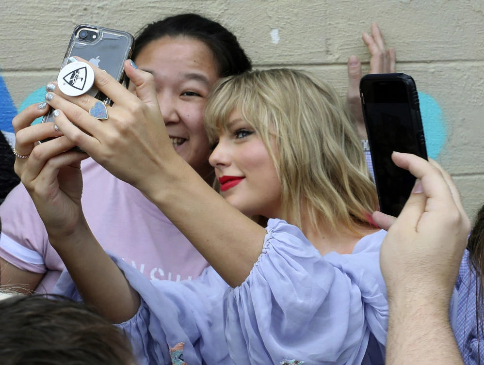 Taylor Swift takes a selfie with a fan at an appearance at a butterfly mural in the Gulch in Nashville, Tennessee on April 25, 2019. (AP)