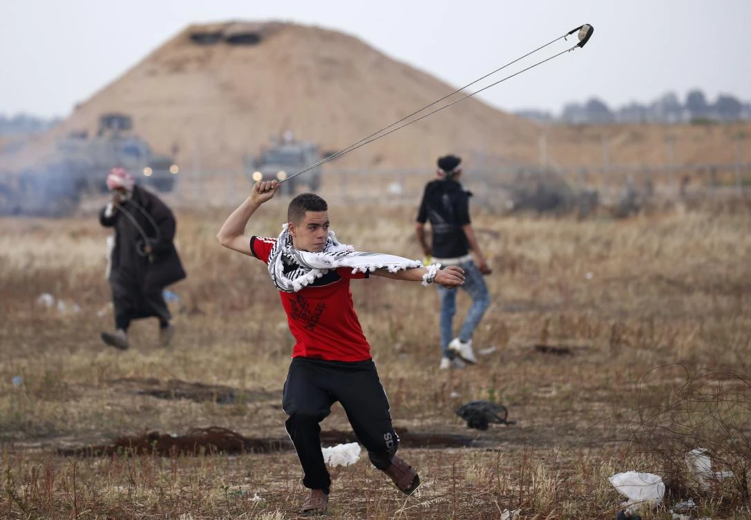 A Palestinian protester uses a slingshot to hurl rocks at Israeli forces during a demonstration near the border with Israel, east of Khan Yunis in the southern Gaza Strip. (AFP)