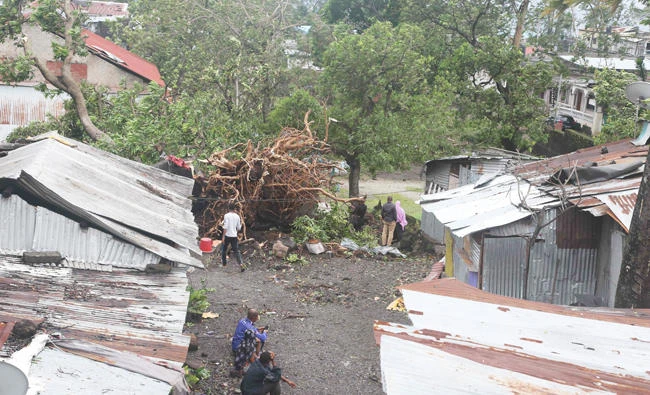 People stand by damaged houses and fallen trees on April 25, 2019 in Moroni after tropical storm Kenneth hit Comoros before heading to recently cyclone-ravaged Mozambique. (AFP)