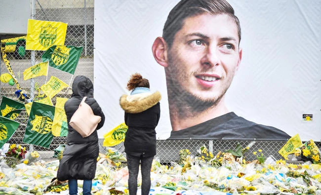 In this file photo taken on February 08, 2019 People look at yellow flowers displayed in front of the portrait of Argentinian forward Emiliano Sala at the Beaujoire stadium in Nantes, on February 8, 2019. (AFP)