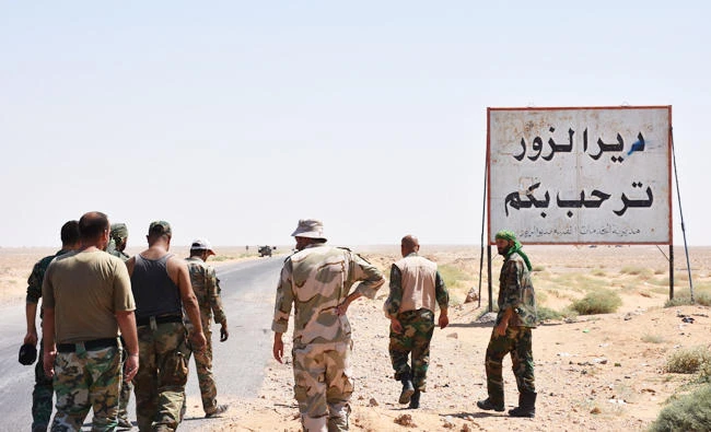 Members of the Syrian government forces stand on the entrance to Deir Ezzor city on September 3, 2017. (AFP)