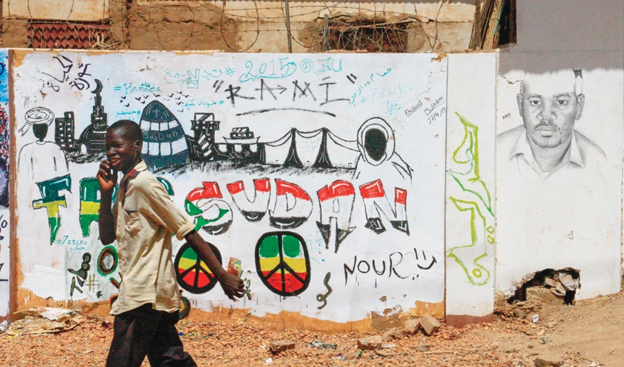 A Sudanese protester walks past a mural outside the army headquarters in Khartoum. (AFP)