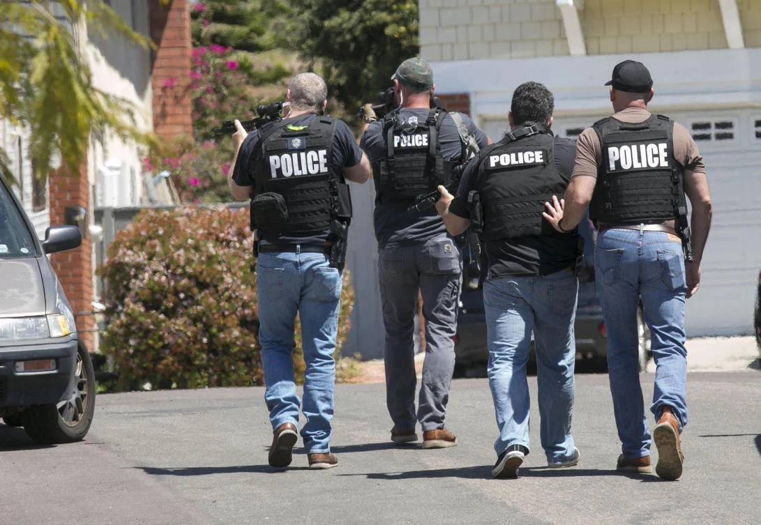 Heavily armed San Diego police officers approach a house thought to be the home of 19 year-old John T. Earnest, who is a suspect in the shooting of several people in a Poway synagogue, on Saturday, April 27, 2019, in San Diego, California A gunman used an AR-type assault weapon to shoot worshippers at Chabad of Poway, San Diego County Sheriff William Gore said. (John Gibbins/The San Diego Union-Tribune/AP)